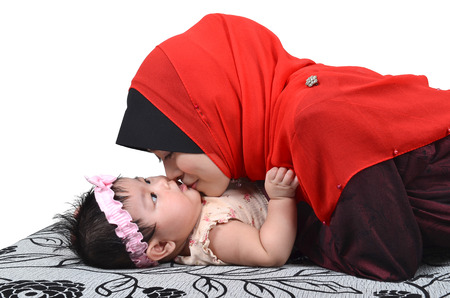Young Asian muslim mother kissing her cute baby girl isolated on white backgroundの写真素材