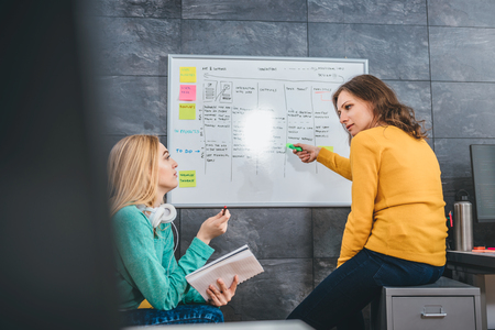 Two business woman having meeting in front of the whiteboardの写真素材