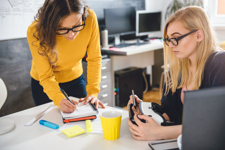 Two business woman working together at the office and testing virtual reality glassesの写真素材
