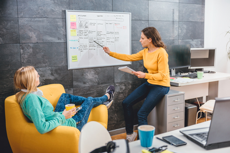 Two business woman having meeting in front of the whiteboardの写真素材