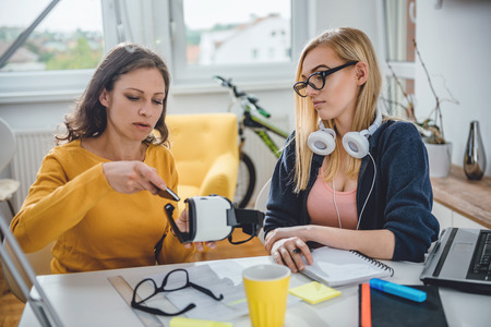 Two business woman working together at the office and testing virtual reality glassesの写真素材