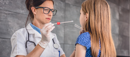 Female pediatrician using a swab to take a sample from a patient's throat