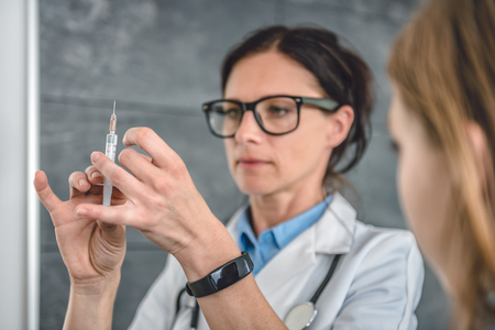 Pediatrics female doctor preparing a vaccine to inject into a patientの写真素材