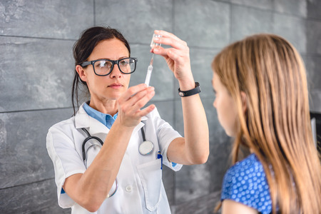 Pediatrics female doctor preparing a vaccine to inject into a patientの写真素材