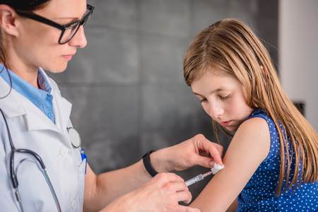 Pediatrics female doctor giving a young girl a vaccine shot in the armの写真素材