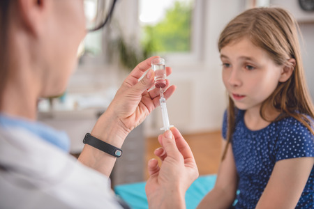 Pediatrics female doctor preparing a vaccine to inject into a patientの写真素材
