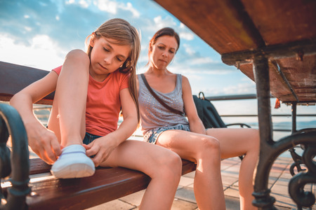 Mother and daughter sitting on the bench by the riverの写真素材