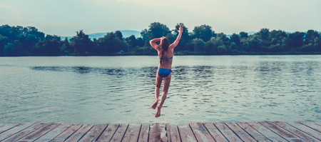 Girl jumping into water from dockの写真素材