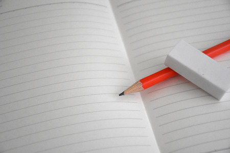 A white note book with lots of room for your text or image and a regular pencil on a wooden deskの写真素材