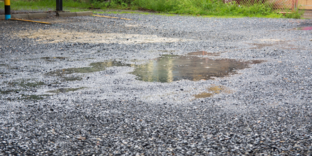 bad quality road with potholes and puddlesの写真素材