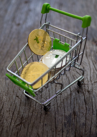 Bitcoin in shopping cart on woodden backgroundの写真素材