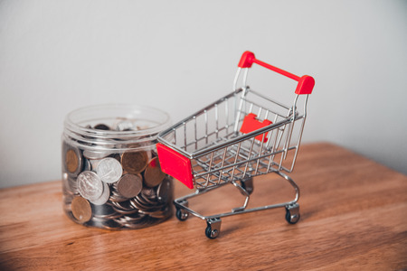 Coins in a wooden bowl on a table and car mart. Money concept.