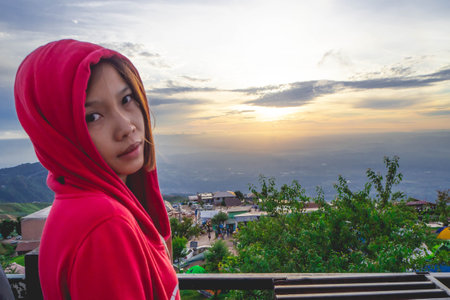 Women wearing red hoods against the morning sky.の写真素材