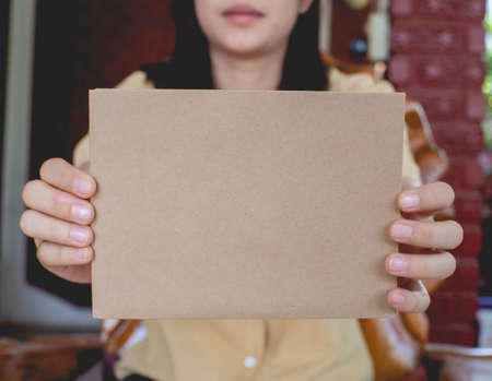 A woman wearing a yellow shirt and holding a paper envelope