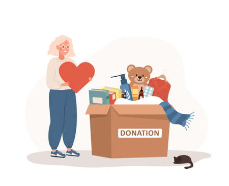 Donation box with clothes, toys, books and medicines. Elderly volunteer woman holding in hands...