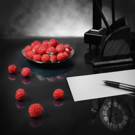First step in the recognition of love to heart's desire. Strawberry symbolizes voluptuousness; reflection clocks and a blank sheet of paper - anticipation. Focus on the pen and berries of foreground. Panoramic image from several pictures.の写真素材
