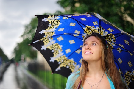 Smiling girl with umbrella under the rainの写真素材