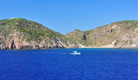 Landscape with a small boat in bright blue seaの写真素材