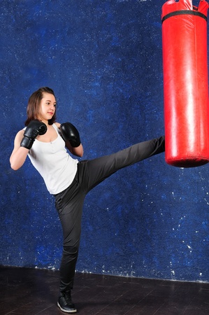 Beautiful sporty girl kicking a punchbagの写真素材
