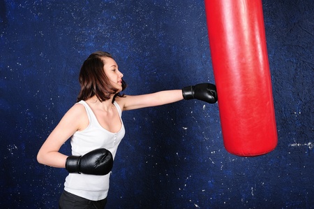 Beautiful young boxer girl hitting a punchbag の写真素材