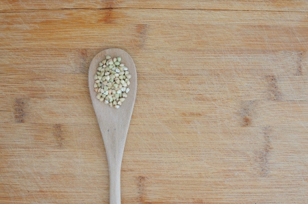 Organic food background with green buckwheat in a wooden tablespoonの写真素材