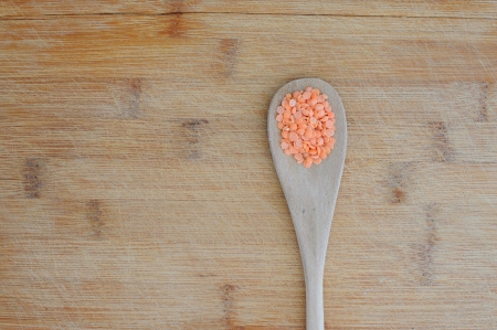 Organic food background with red lentil in a wooden tablespoonの写真素材
