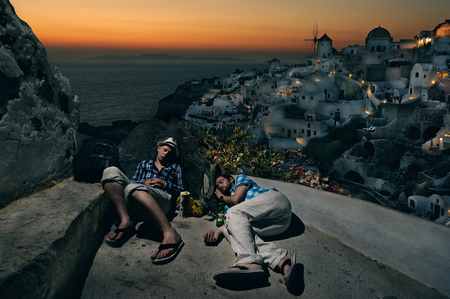 Young tourists with backpacks sleeping at the Oia village, Santorini island, Greeceのeditorial素材