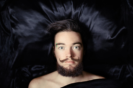 Portrait of a bearded man lying on a silk beddingの写真素材