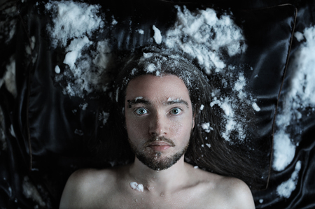Portrait of a bearded man lying on a silk bedding covered with snowの写真素材