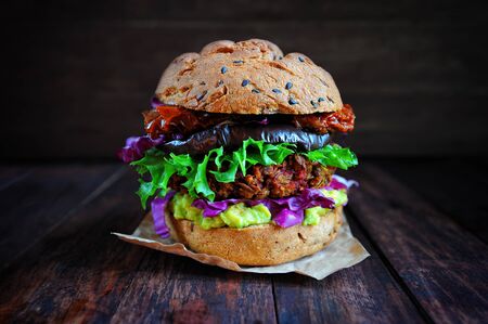 Fresh beetroot lentil vegan burger with grilled eggplant, sun-dried tomatoes, guacamole sauce and rye buns. Vegan food conceptの写真素材