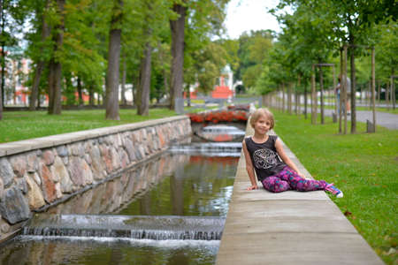 August, 2015 - Tallinn, Estonia. Kadriorg park. A girl is sitting nera the water channel in the park.のeditorial素材