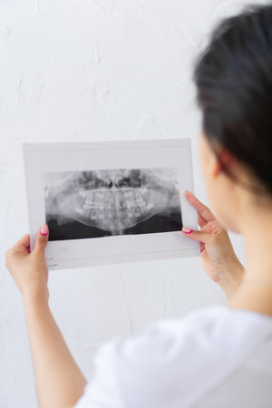 Concept dentistry. blur Doctor watches to black and white picture. From behind of Young woman...