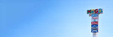 russian shopping mall signboards pointer on sky gradient background. Auchan mega ikea leroy merlin mega card lettering, from MEGA hardware store. extra wide banner, copy spaceのeditorial素材