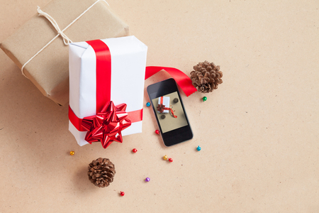 The gift box was placed with decorations items of Christmas day. Concept that was changed by the era. Until the modern era, giving gifts is easy through smart phone.の写真素材