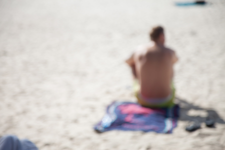 The young man was sunbathing on the sand by sitting and blurry of picture.の写真素材
