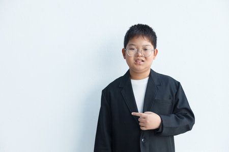 An Asian boy in a suit is pointing to the side in the blank space for text.の写真素材