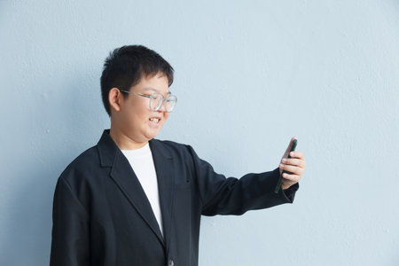 An Asian boy in a business suit is taking a selfie with space left for text.の写真素材