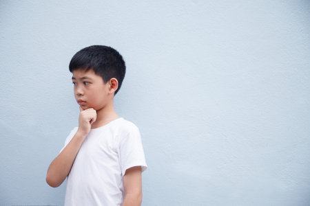 The boy is deep in thought, against a gray background with space for text.