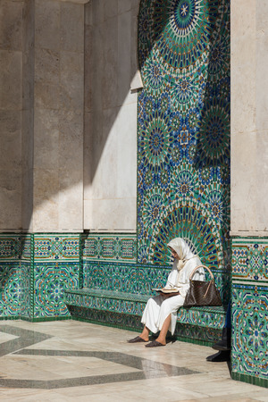 Casablanca, Morocco - March 21, 2014: One muslim woman sits in front of the colourful mosaic and reads book in Grand Mosque of Hassan II on March 21, 2014 in Casablanca, Moroccoのeditorial素材