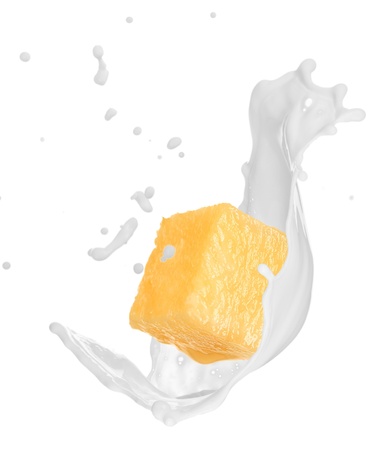 Piece of pine apple with milk splash over white の写真素材
