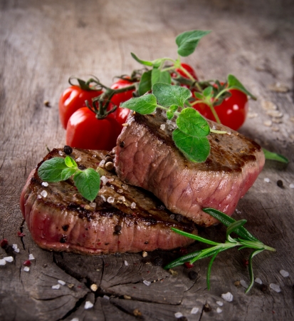 Grilled bbq steaks with fresh herbs and tomatoesの写真素材