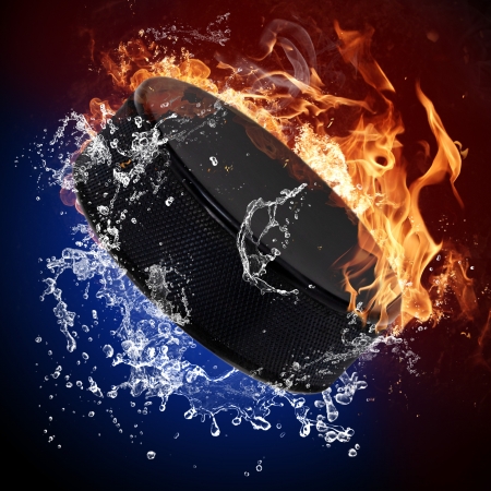 Hockey puck in fire flames and splashing waterの写真素材