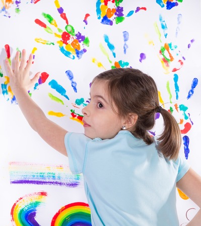 Beautiful little girl with hands in the paint over whiteの写真素材