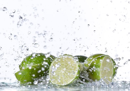 Limes with water splash isolated on white
