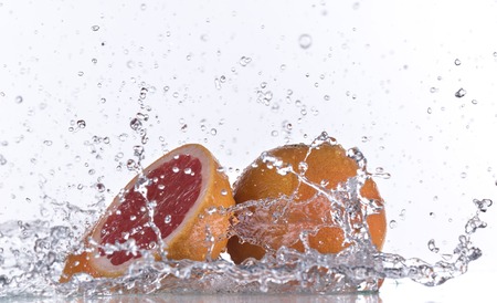 Grapefruit with water splash isolated on whiteの写真素材