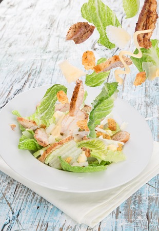 Caesar salad with chicken and greens on wooden tableの写真素材