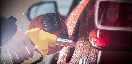 Hand refilling the car with fuel, close-up 