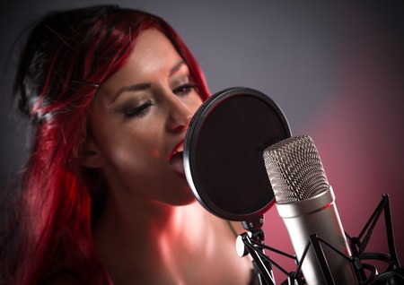 Young singer screaming on the studio microphoneの写真素材