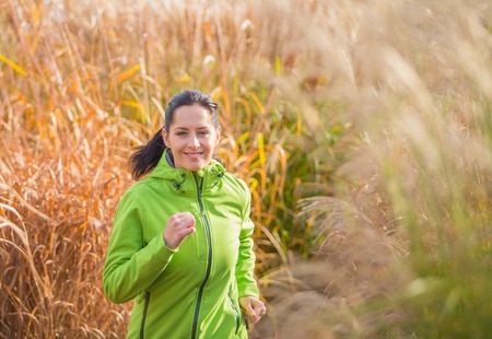 Young happy brunette woman training outside during autumn day and listening to music.