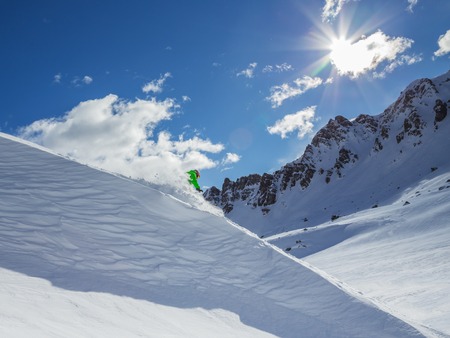 Skier skiing downhill in high mountains during sunny day.の写真素材